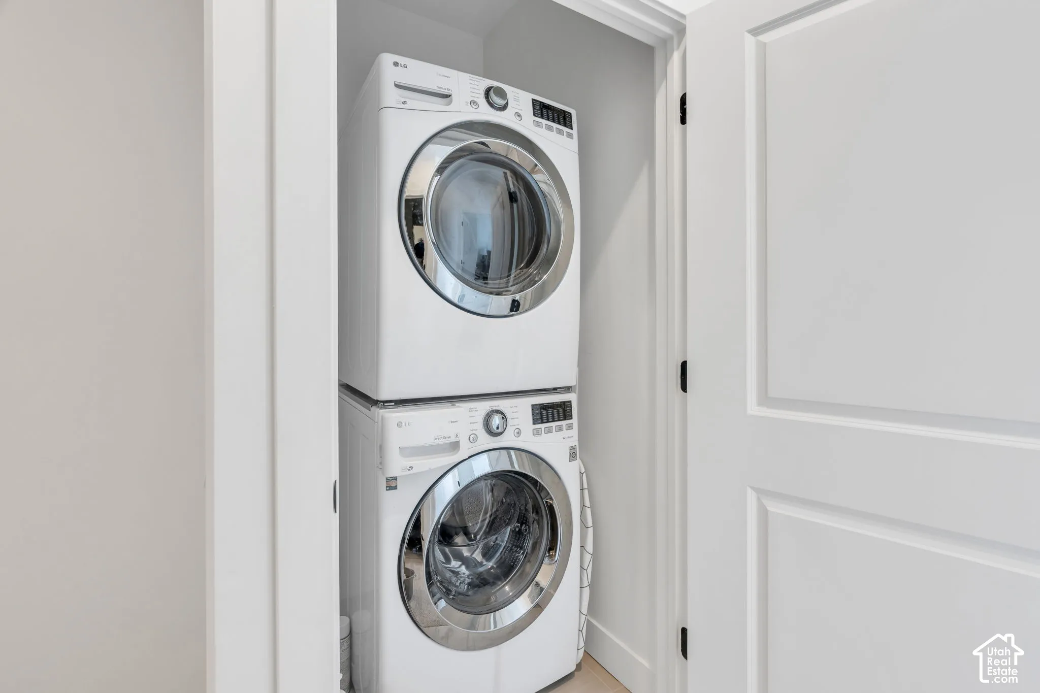 Dedicated laundry closet featuring a stacked white front-load washer and dryer set, enclosed by a white paneled door