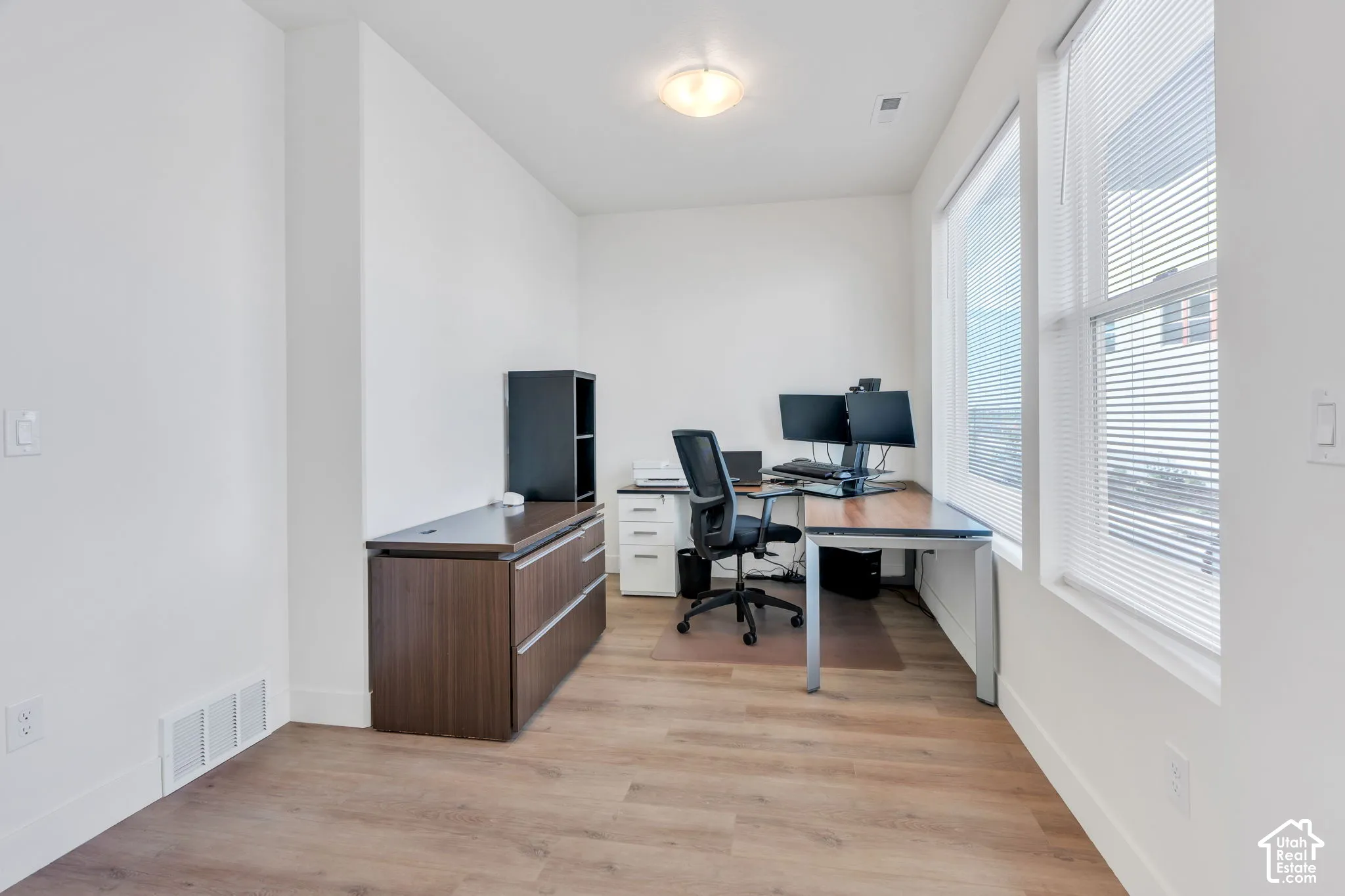 Interior space featuring neutral wall paint, wood-finish flooring, and large windows with horizontal blinds