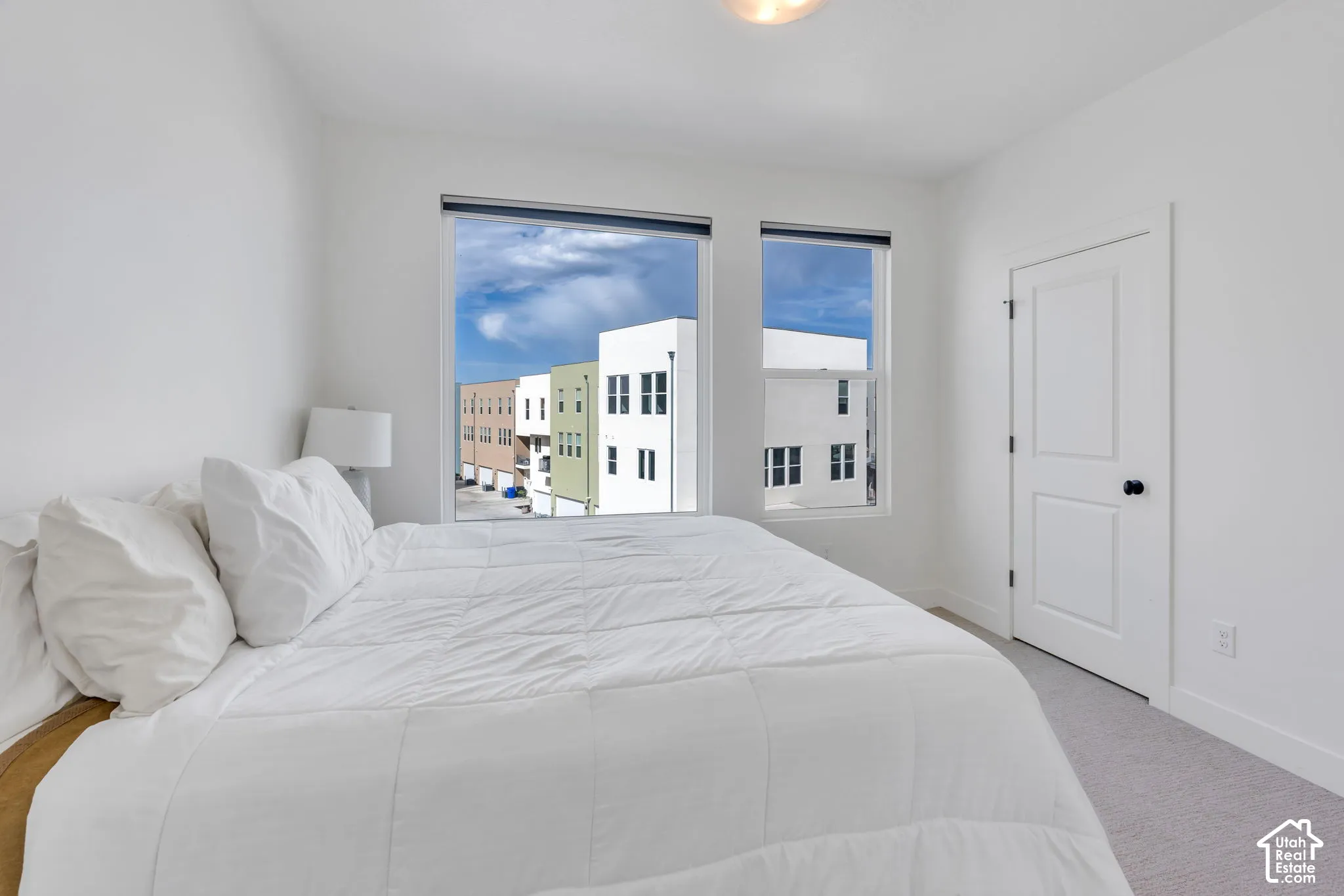 Neutral-toned interior featuring dual windows, high-contrast matte black hardware, and wall-to-wall carpeting