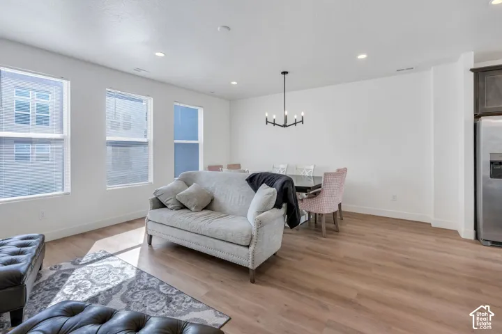 Open-concept interior featuring wood-finish flooring, recessed lighting, a modern multi-arm chandelier, and large windows