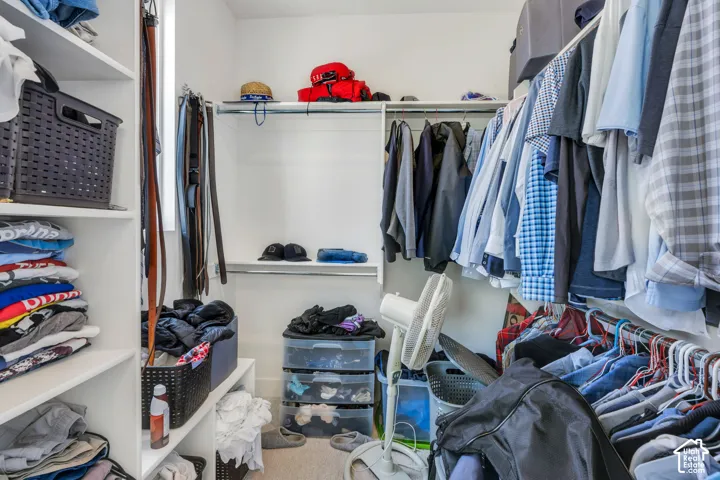 Walk-in closet featuring white built-in shelving and multi-level metal garment rods