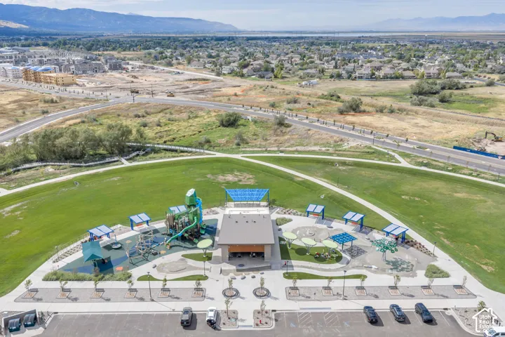 Community recreation area featuring a pavilion, playground structure, splash pad, shaded seating areas, and concrete pathways