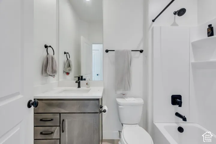 Bathroom featuring a grey-toned vanity with a white countertop and rectangular undermount sink, complemented by matte black plumbing fixtures, hardware, and accessories, along with a full-height wall mirror and a white tub-shower enclosure