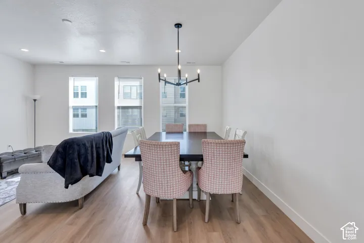 Open-concept space featuring wood-finish flooring, recessed lighting, a modern multi-arm chandelier, and tall windows