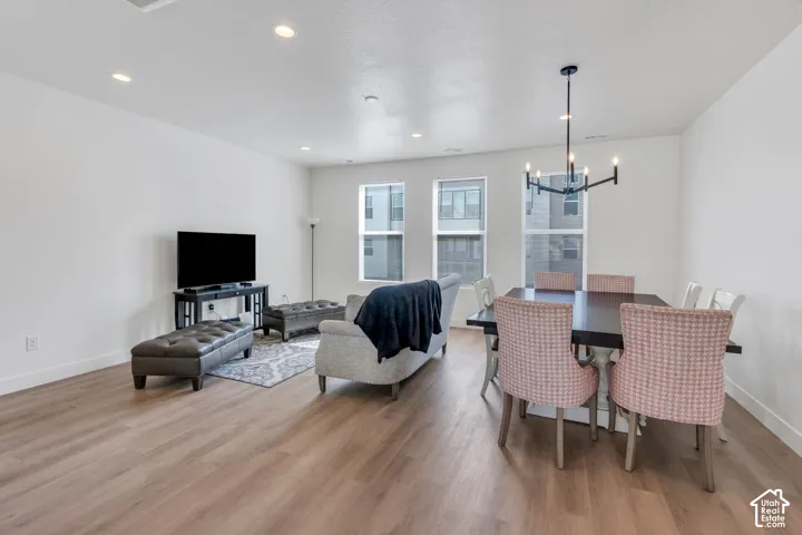 Open-concept room featuring wood-finish flooring, recessed lighting, expansive windows, and a modern multi-arm chandelier