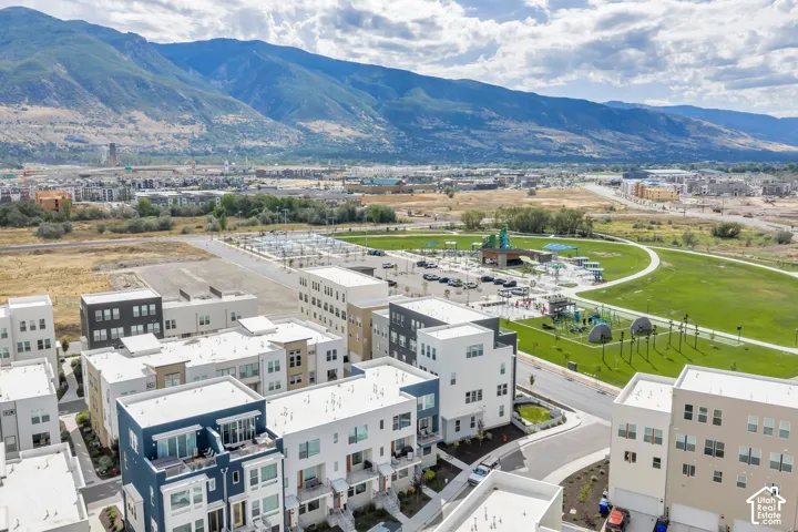 Aerial perspective of a multi-story residential community featuring flat rooflines, a combination of dark-tone and neutral exterior siding, private balconies, and an expansive mountain backdrop