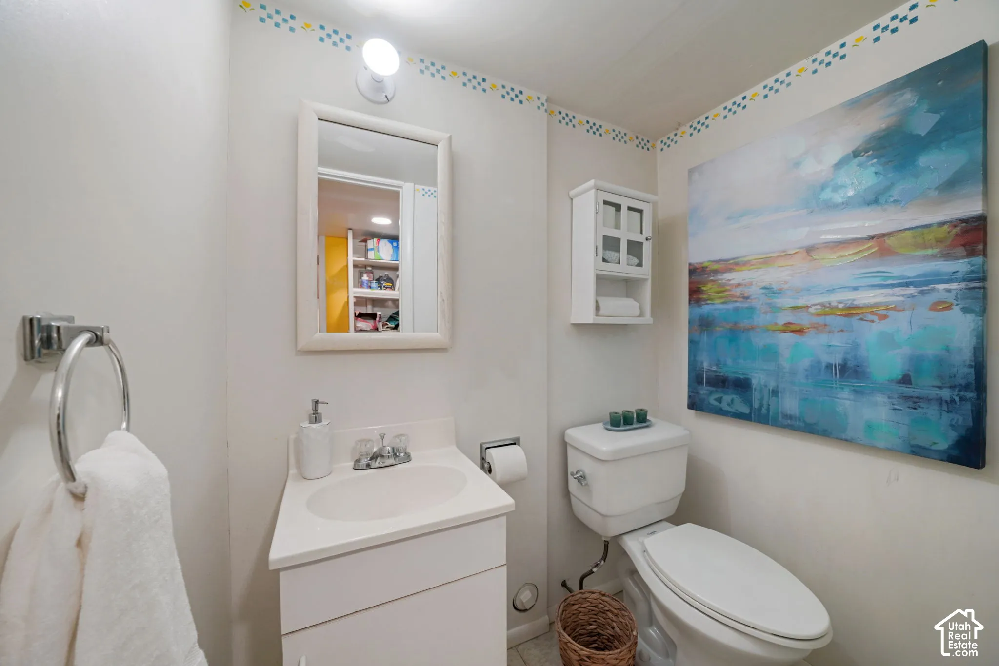 Bathroom featuring a white pedestal vanity, chrome dual-handle faucet, framed wall mirror, and wall-mounted storage cabinet