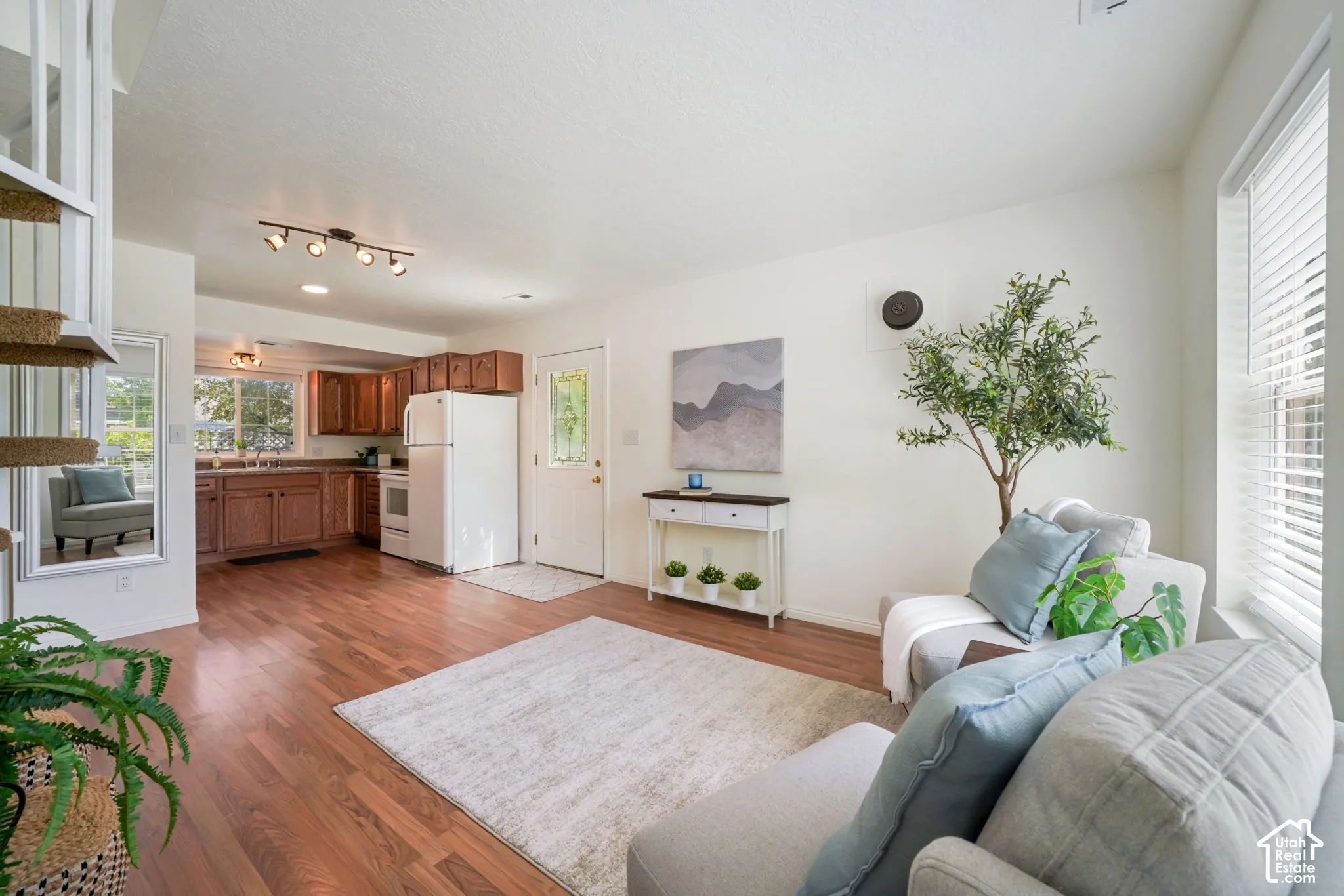 Open-concept interior featuring wood-finish flooring, natural light through double-pane windows, and a kitchen equipped with wood cabinetry