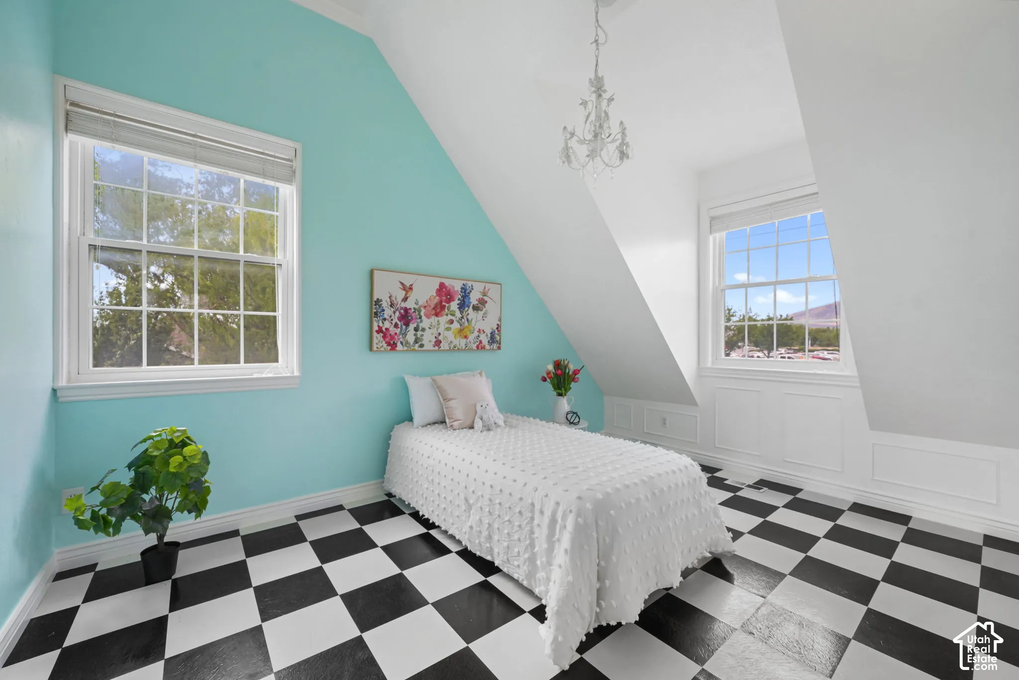 Room featuring vaulted ceilings, checkered pattern flooring, two double-hung windows, decorative wall molding, and a traditional chandelier