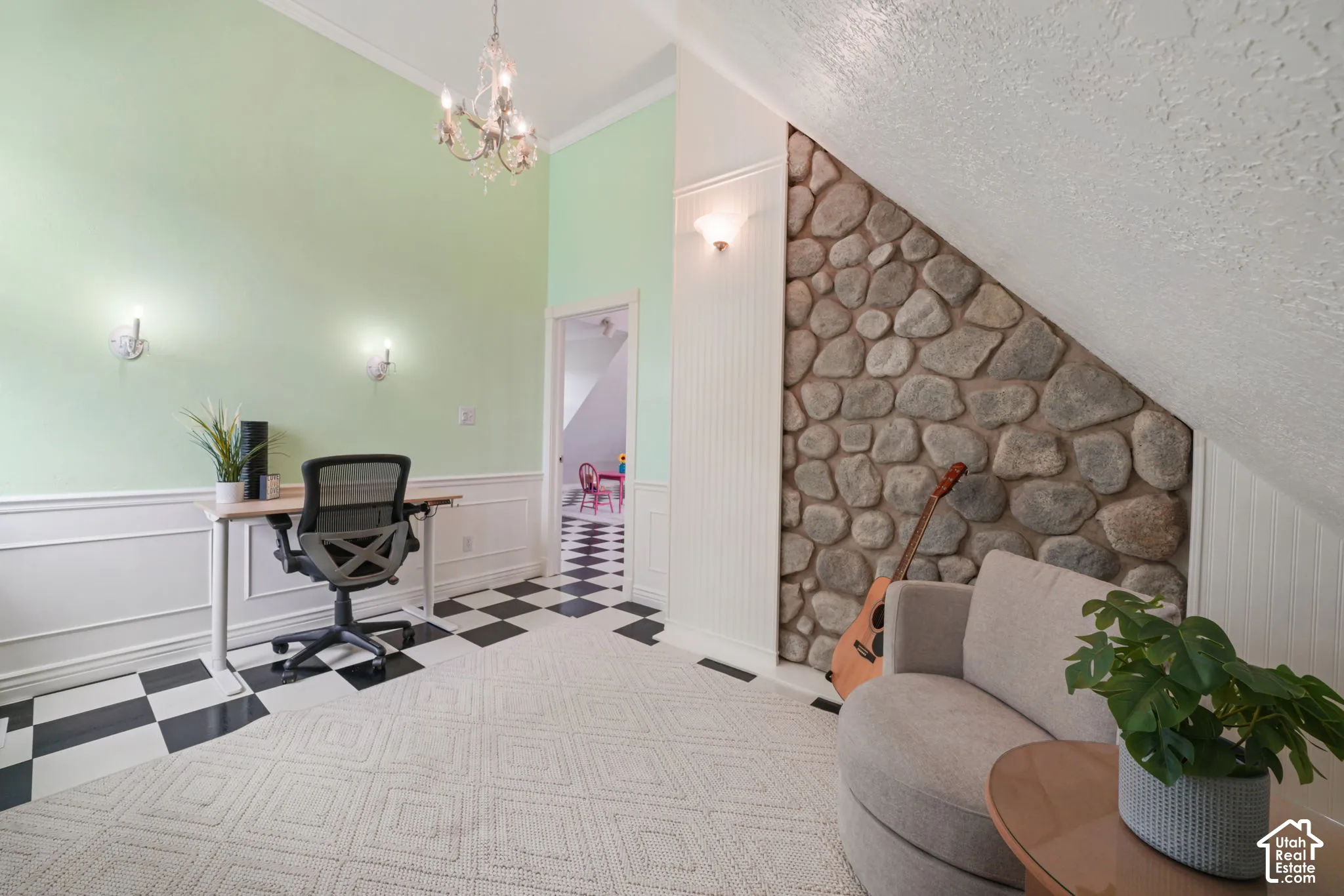 Vaulted ceiling featuring a natural stone accent wall, decorative beadboard paneling, classic wainscoting, and a multi-arm chandelier