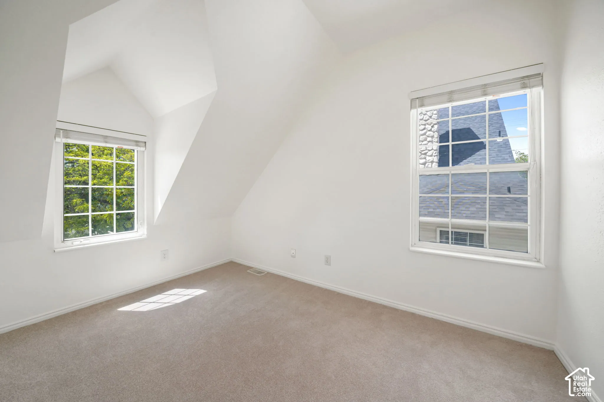 Room featuring vaulted ceilings, carpeted flooring, and two dual-pane grid windows
