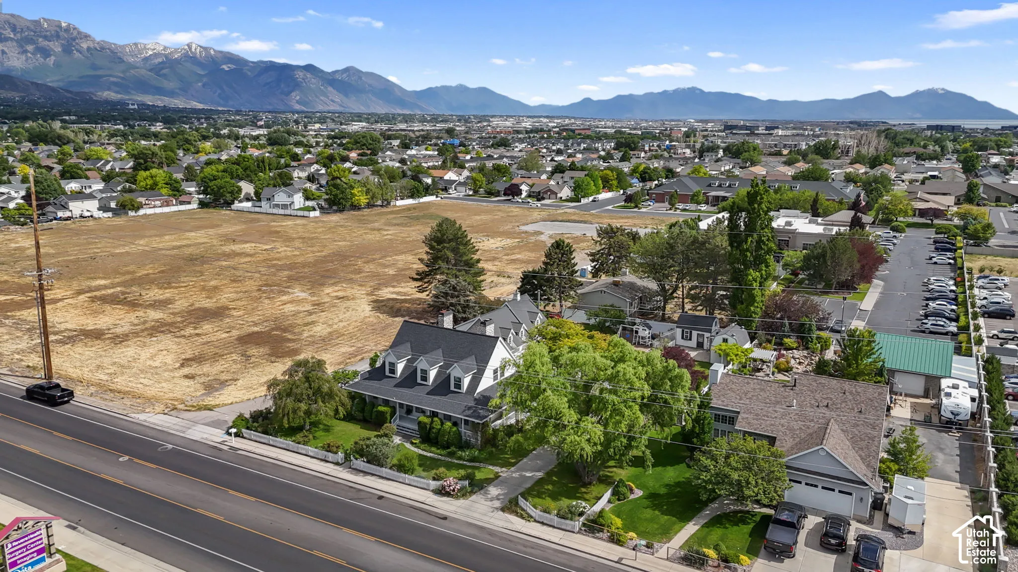 Aerial view featuring a multi-gabled exterior, mature landscape, detached garage structure, and mountain backdrop