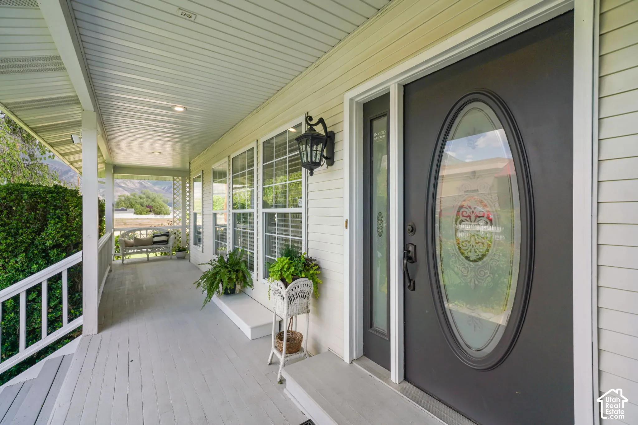 Covered porch featuring lap siding, recessed lighting, wall-mounted lantern-style sconces, and an entry door with an oval glass insert and a decorative sidelight