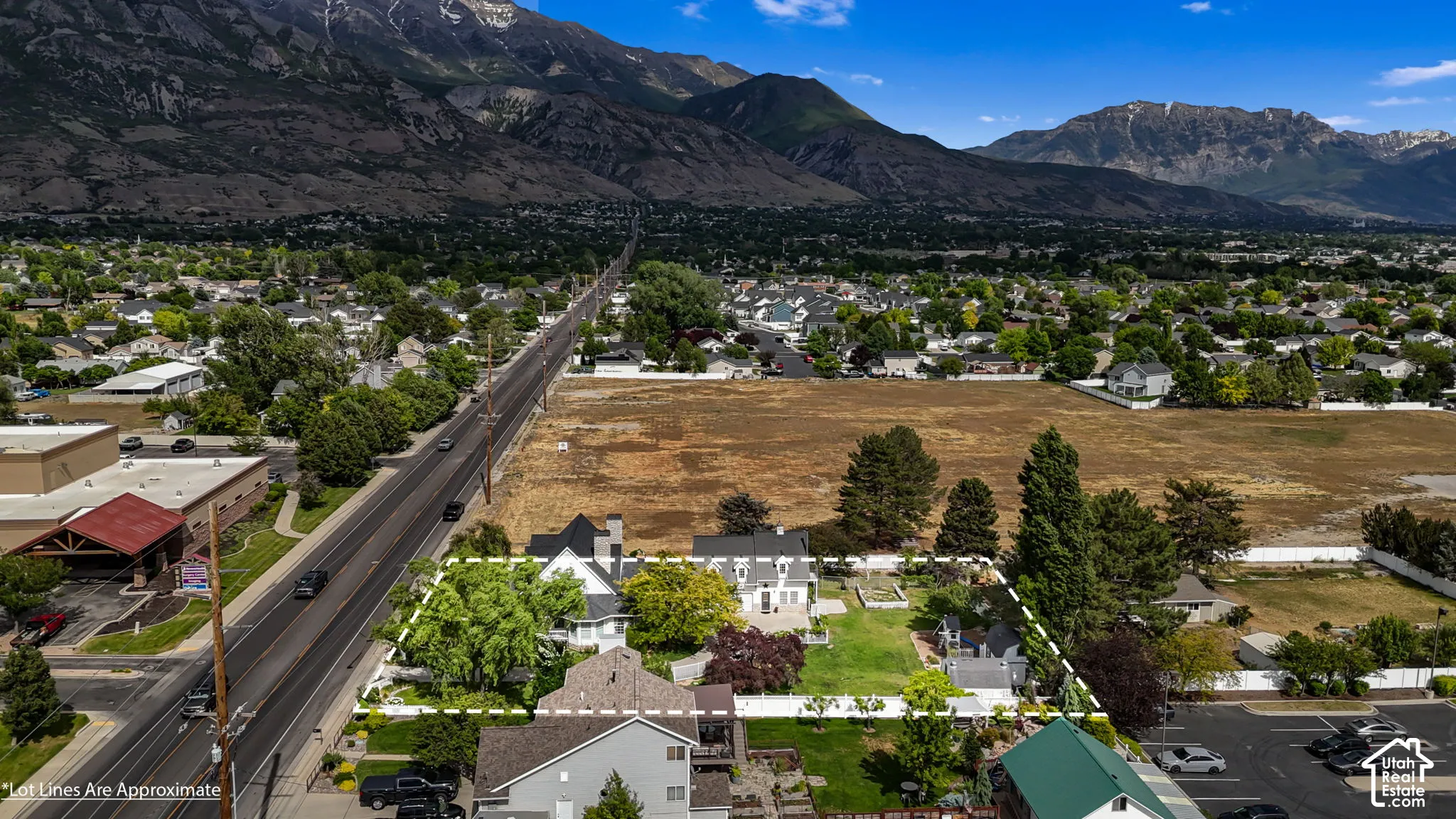 Aerial perspective of a property lot featuring mature landscaping, an enclosed backyard area, and mountain scenery