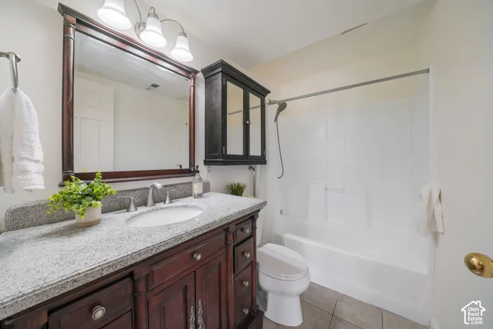 Bathroom featuring a dark-finish wood vanity with a speckled countertop, integrated sink, matching wall-mounted medicine cabinet, tri-light fixture, and a white tub-shower combination