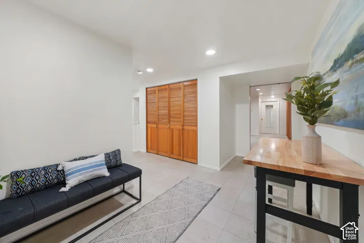 Neutral-toned tile flooring, recessed ceiling lighting, and built-in closet with wooden louvered doors