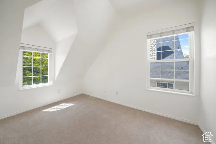 Room featuring vaulted ceilings, carpeted flooring, and two dual-pane grid windows