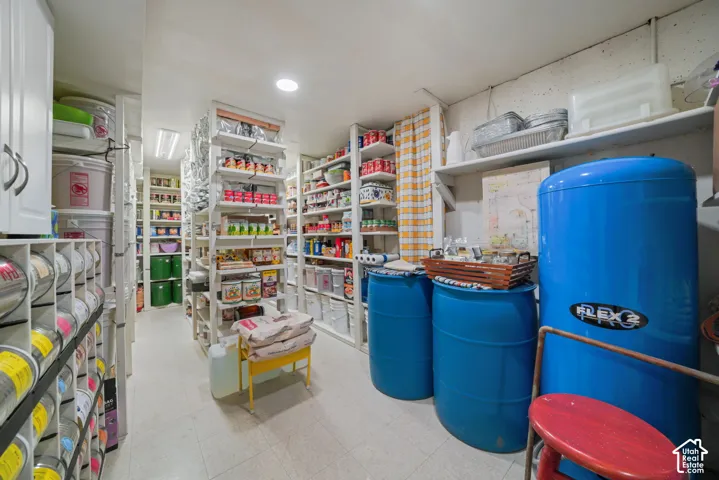 Storage room featuring multiple levels of white metal shelving units and recessed ceiling lighting
