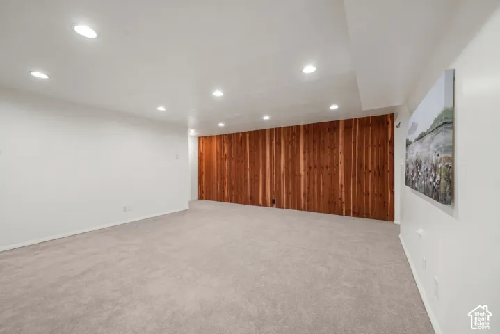Interior space featuring wall-to-wall carpeting, recessed ceiling lighting, and a vertical wood-plank accent wall