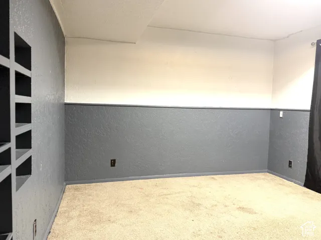 Room featuring two-toned textured wall finishes, integrated wall shelving, and carpeted flooring
