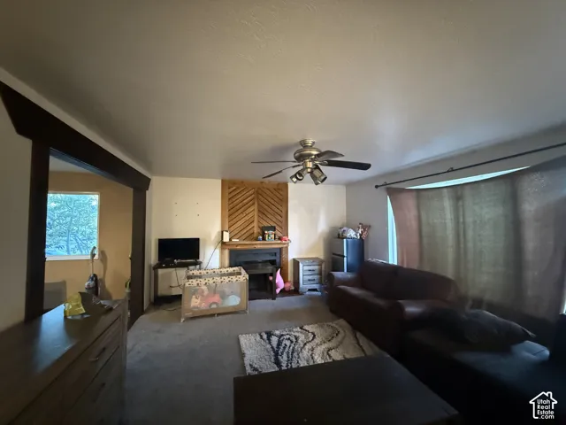 Living area featuring a fireplace with a chevron-patterned wood surround, large picture window, and ceiling-mounted light fixture