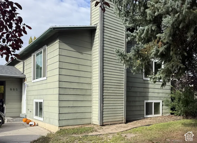 Exterior facade featuring horizontal siding, a prominent chimney, and a concrete driveway