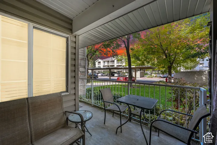 Covered patio featuring concrete flooring, white metal railing, and horizontal vinyl siding