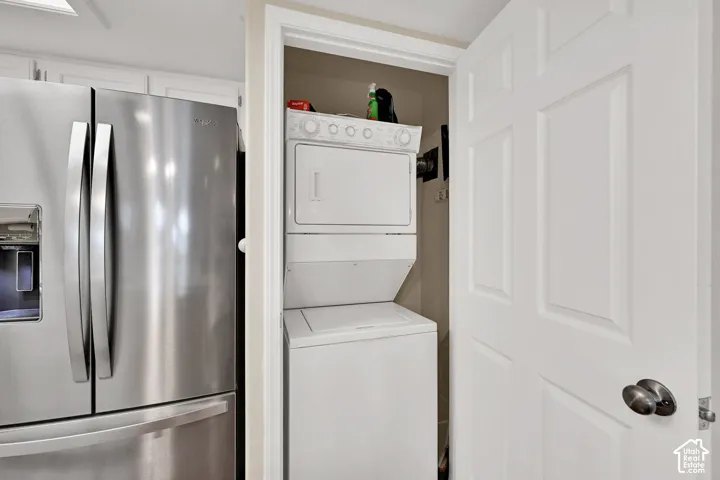 Stainless steel French door refrigerator with an external water and ice dispenser, paired with a stacked laundry unit featuring a white finish