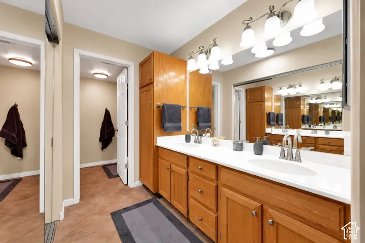Double vanity featuring wood cabinetry, solid surface countertops, dual undermount sinks, and multi-light fixtures