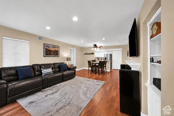 Open-concept interior featuring wood-finish flooring, recessed lighting, a fireplace mantle, and built-in white cabinetry