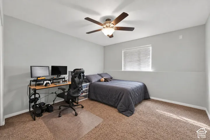 Neutral-toned walls, wall-to-wall carpeting, window with integrated blinds, and a multi-blade ceiling fan with central lighting