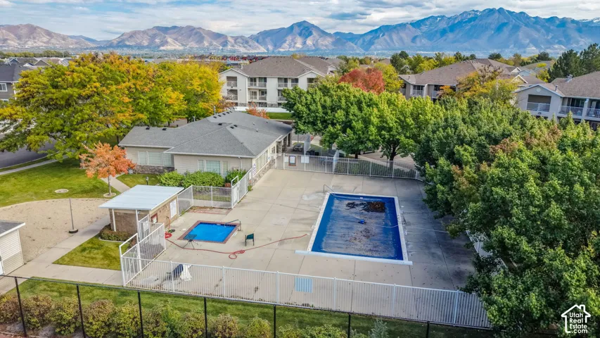 Community amenities featuring an outdoor swimming pool, spa, fenced perimeter, and mountain backdrop