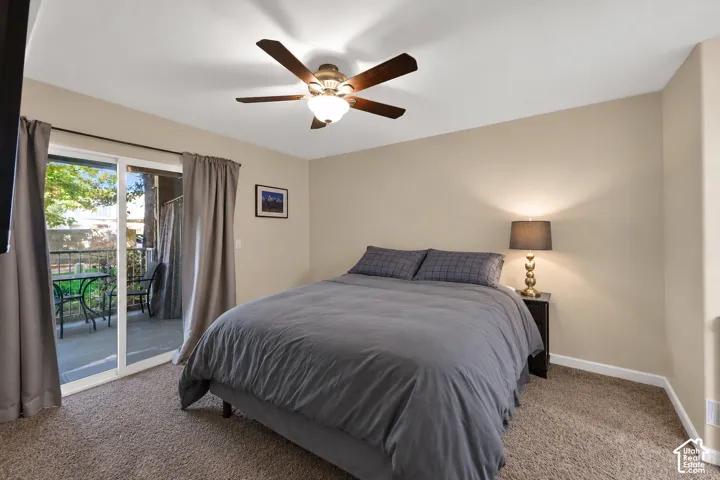 Carpeted bedroom featuring a multi-speed ceiling fan with integrated light fixture and sliding glass door with external balcony access