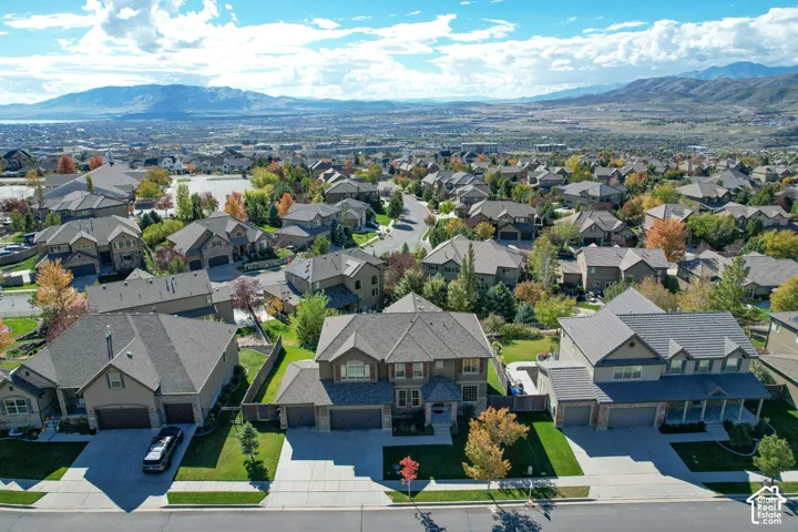 Aerial perspective of residential neighborhood featuring multi-level dwellings with pitched shingle roofing, multi-car garages, paved driveways, and mountain backdrop