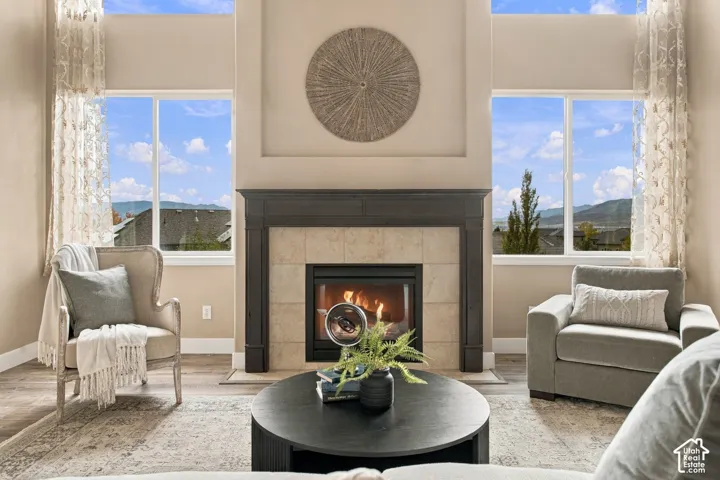 Vaulted ceilings featuring double-stacked windows, centered by a fireplace with a deep-tone wood mantle and stone-tile surround