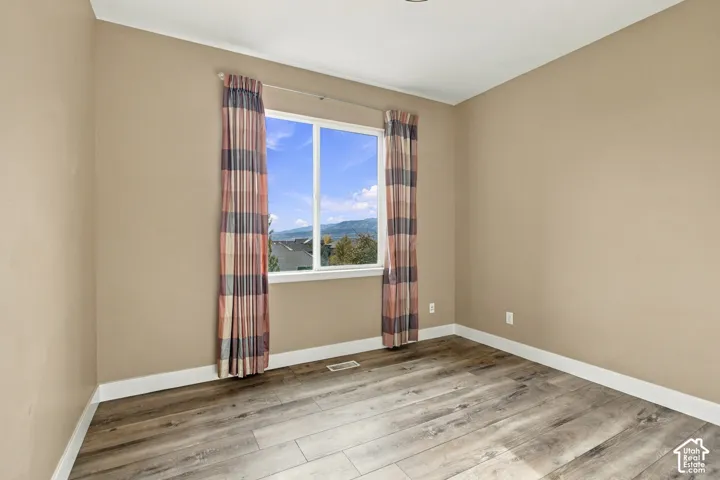 Neutral-toned interior space featuring wood-finish flooring and a single-pane window with mountain scenery