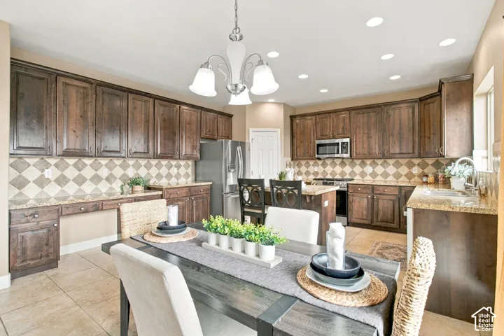 Kitchen featuring stained wood cabinetry, stone countertops, diamond-patterned tile backsplash, recessed lighting, and a multi-arm chandelier