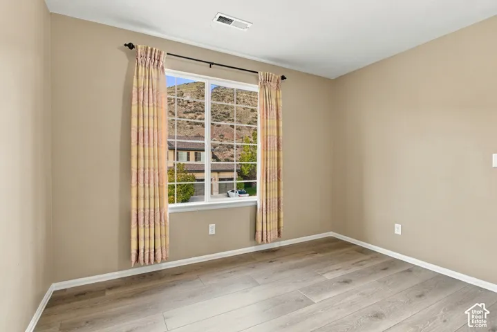 Room featuring wood-finish flooring, neutral wall paint, and a window with mountain scenery