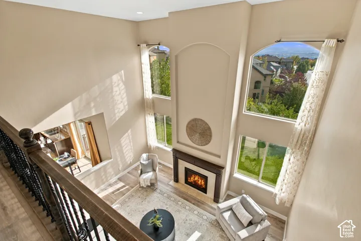 Two-story living area featuring vaulted ceilings, a fireplace with a dark wood mantel, tiered arched windows, and wood-finish flooring