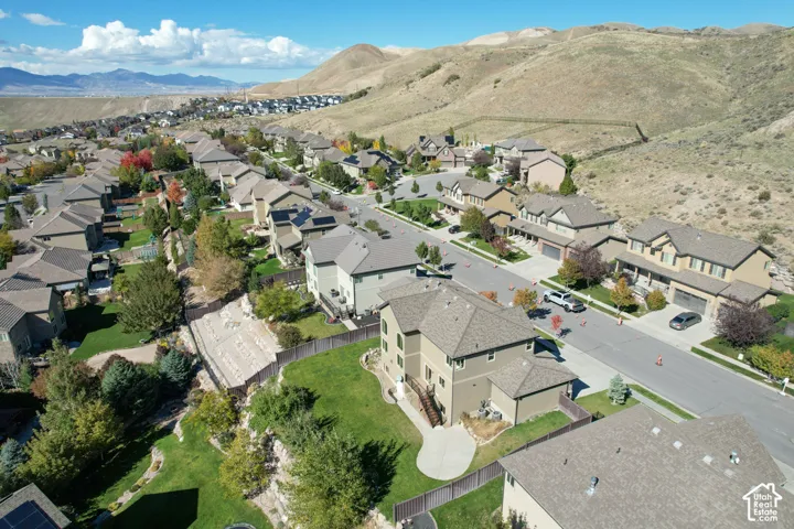 Aerial perspective featuring multi-story residential architecture, concrete driveways, manicured lawns, fenced backyards, and expansive mountain terrain