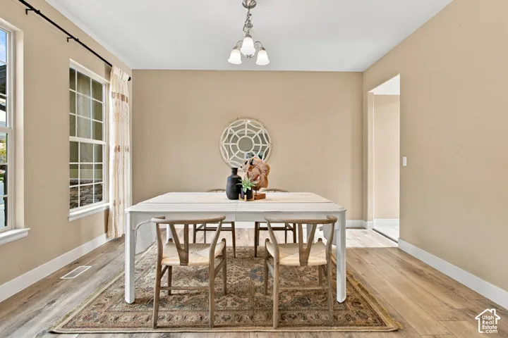 Dining area featuring wood-finish flooring, dual windows, and a three-light pendant fixture