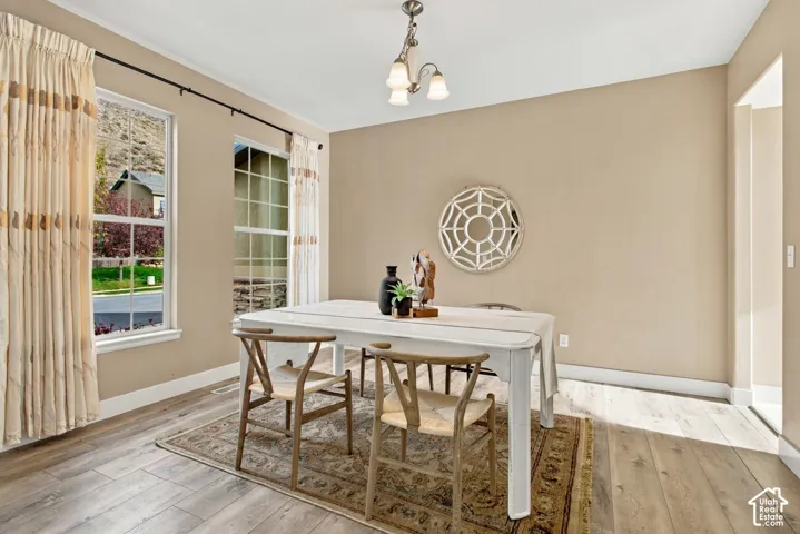 Neutral-toned walls, wood-finish flooring, dual windows with exterior mountain scenery, and a three-light chandelier