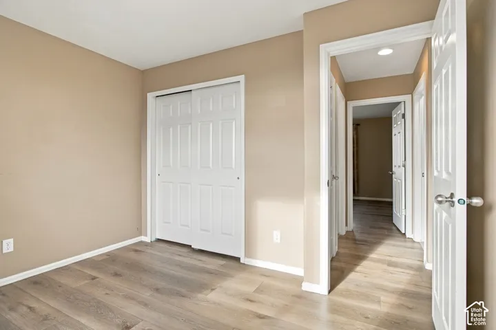 Room featuring wood-finish flooring, white six-panel interior doors, and a sliding-door closet