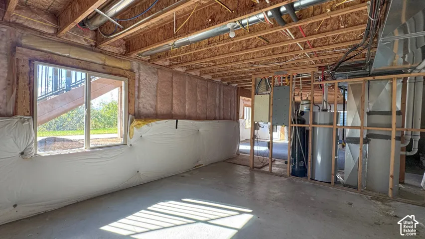 Unfinished lower level with exposed ceiling joists, concrete flooring, exterior-grade window, wall insulation, and mechanical systems