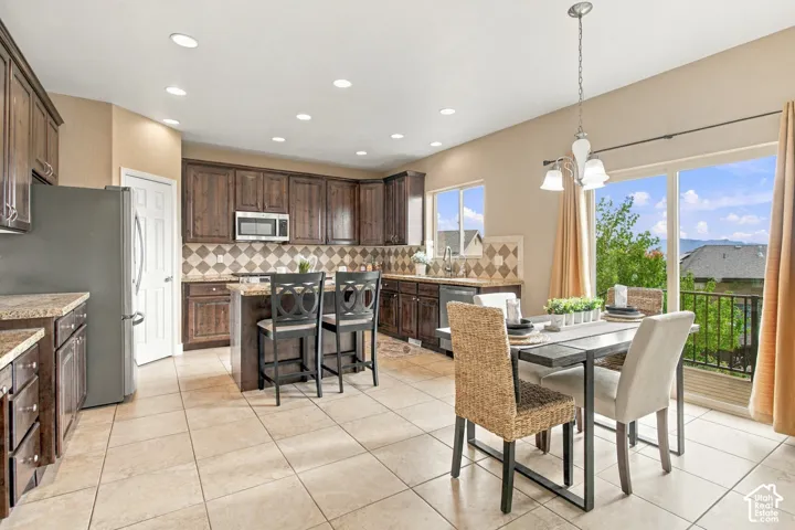Kitchen featuring stained wood cabinetry, stone-finish countertops, tile backsplash, recessed lighting, and tile flooring