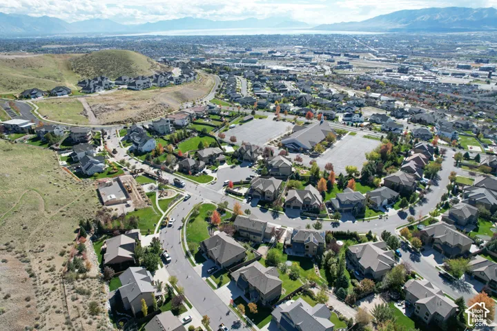 Aerial perspective featuring rolling hillside terrain, paved street infrastructure, residential clusters, mature trees, and a mountain range backdrop