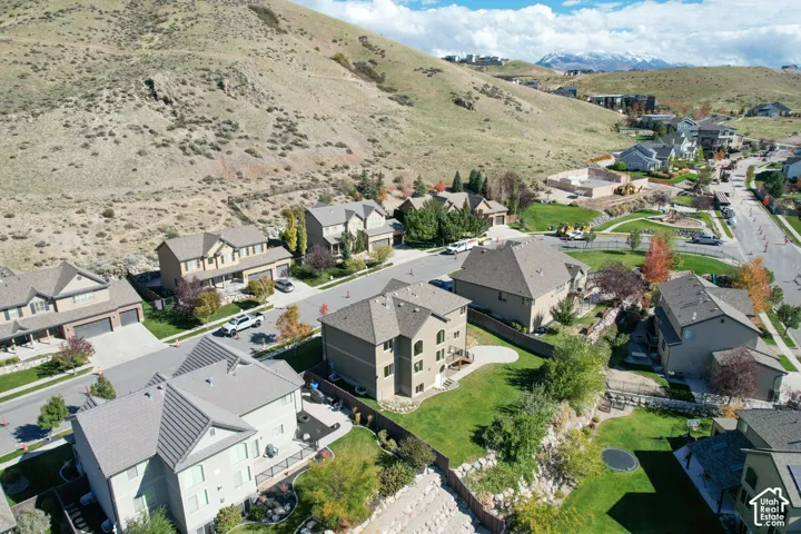Aerial view of a residential neighborhood featuring multi-story homes, expansive hillside terrain, and manicured green spaces
