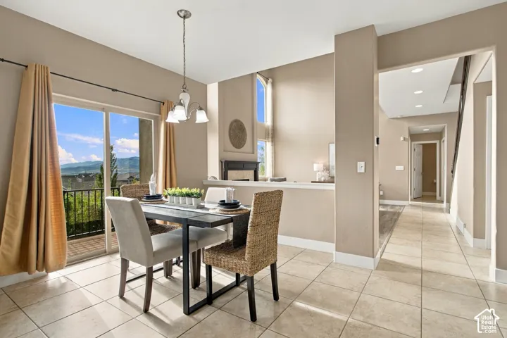 Dining area featuring ceramic tile flooring, a multi-light pendant chandelier, sliding glass doors, and mountain scenery