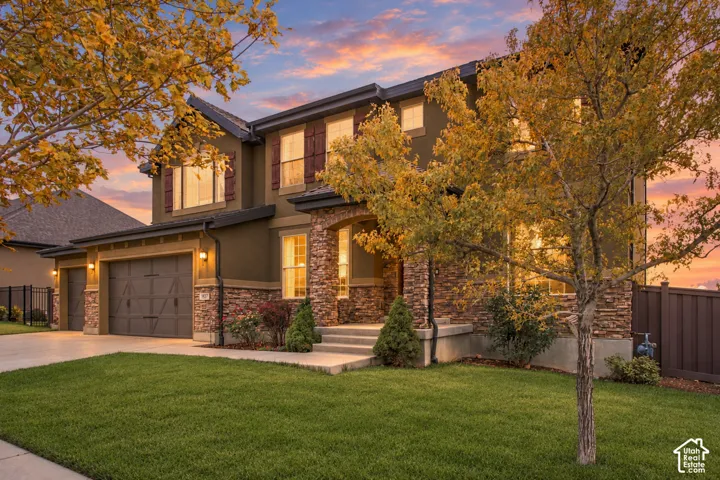 Two-story residence featuring stone veneer masonry, horizontal siding, carriage-style garage doors, and a covered entry