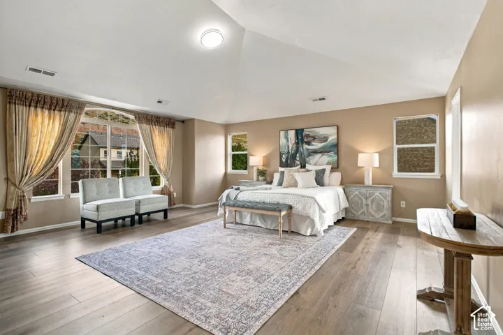 Spacious room featuring a high vaulted ceiling, wood-finish flooring, and a large arched window